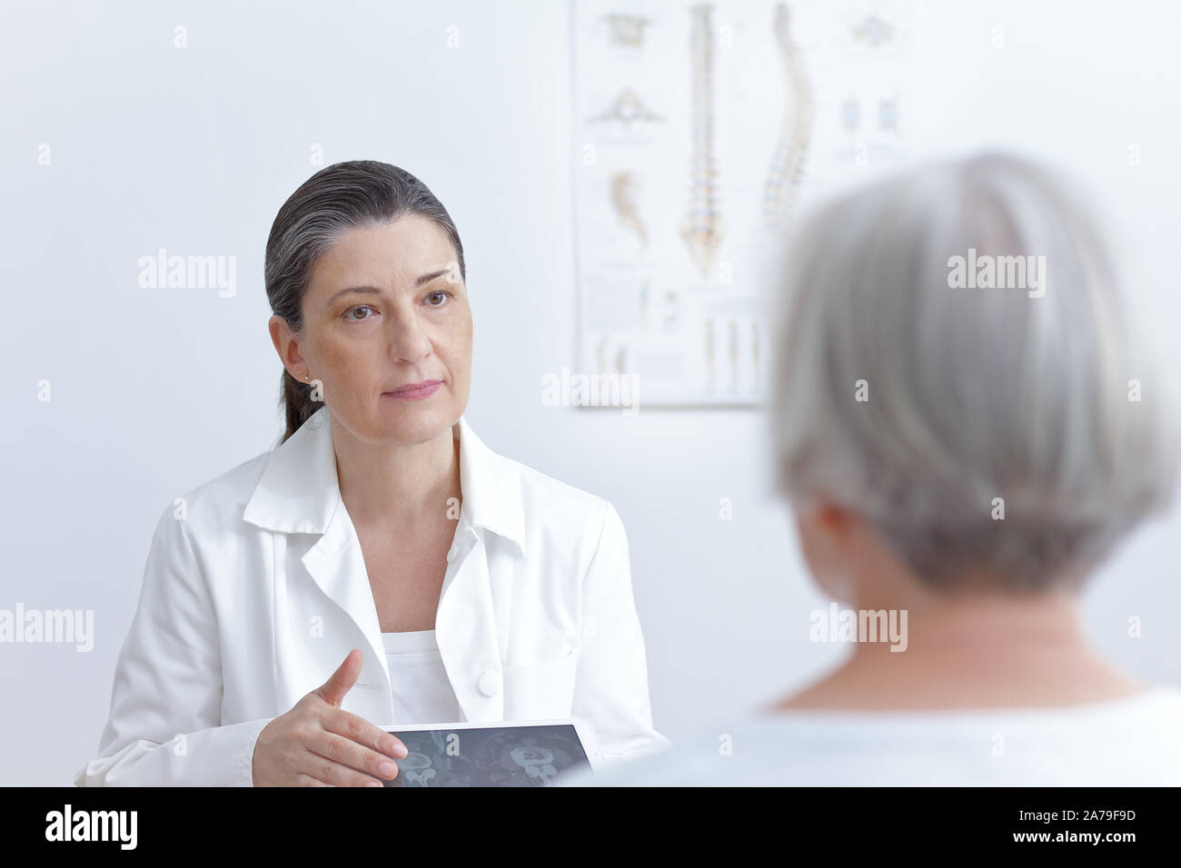 Frau Doktor mit Tablet Computer mit Ihrer älteren Patienten Katze Bilder Ihrer degenerierten Wirbel zu scannen. Stockfoto