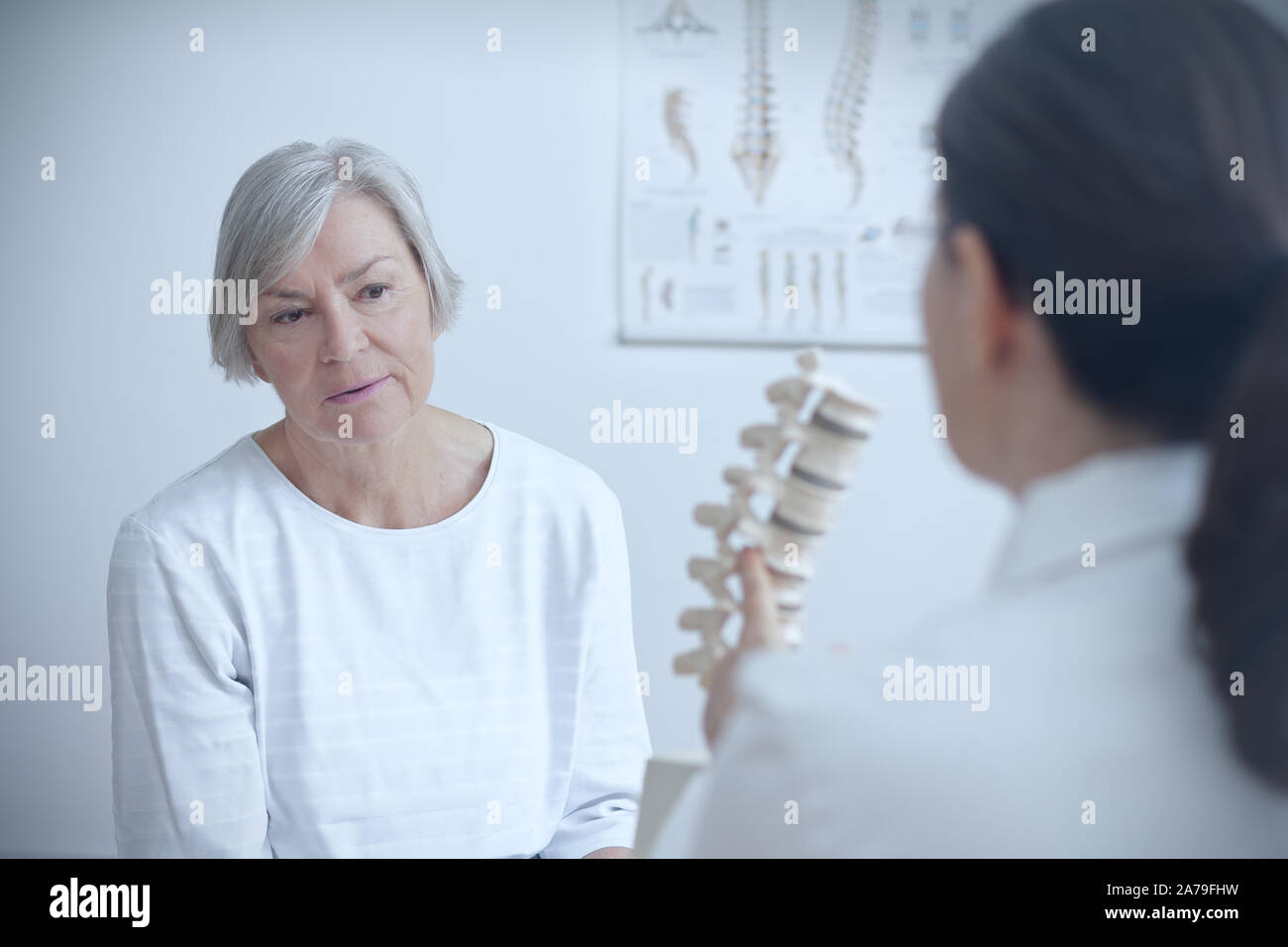 Altern und Rückenschmerzen Konzept: Arzt für Orthopädie mit Ihrer älteren Patienten ein Degenerierter Disk auf einem Backbone Modell. Stockfoto