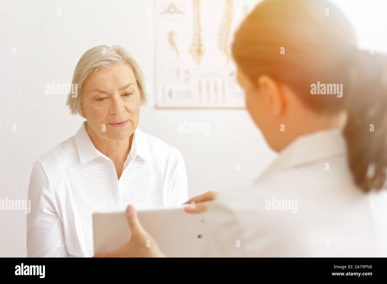Ältere Frau mit ihrem Arzt für Geriatrie zeigen ihr das Labor die Ergebnisse der neuesten Tests auf einem Tablet-PC. Stockfoto