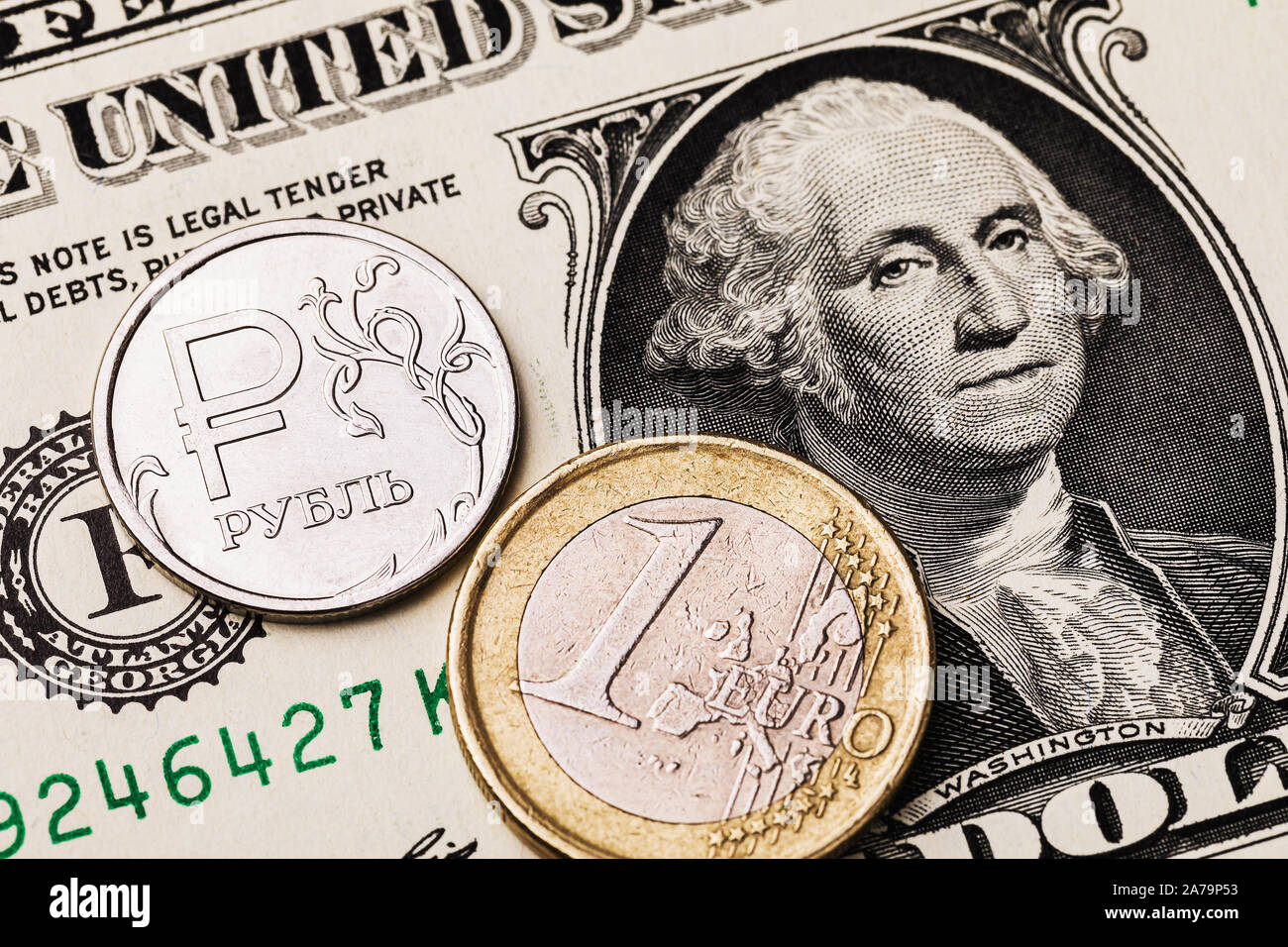 Ein Euro Münze und Russische Rubel vor dem Hintergrund von einem Dollar Bill. Die Münze hat eine Inschrift in russischen Buchstaben Rubel Stockfoto