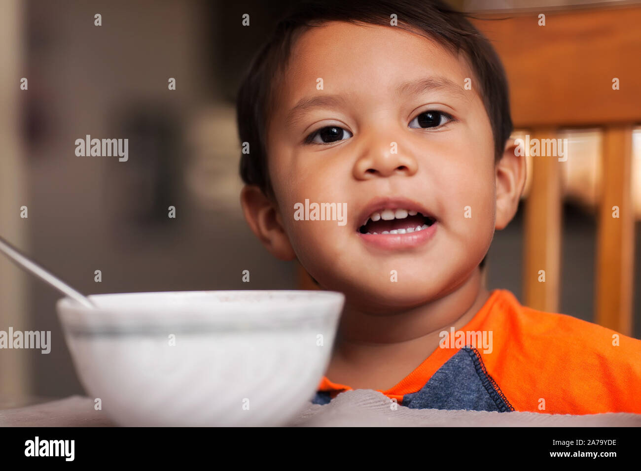 Ein Hispanic junge am Tisch mit einer Schale, Löffel und bereit Frühstück zu essen. Stockfoto