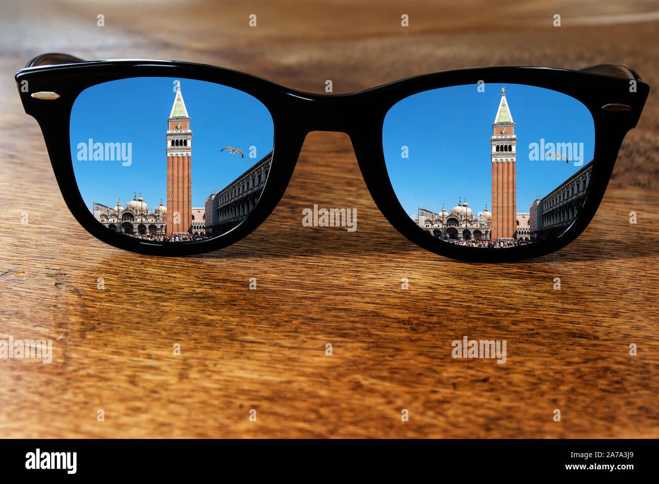 Sonnenbrille auf einen hölzernen Tisch reflektiert den Markusplatz Stockfoto