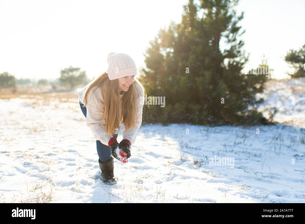 Liebespaar spielen Schneebälle im Winter im Wald. Mädchen formt und wirft Schneebälle. Lachen und eine gute Zeit haben. Stockfoto