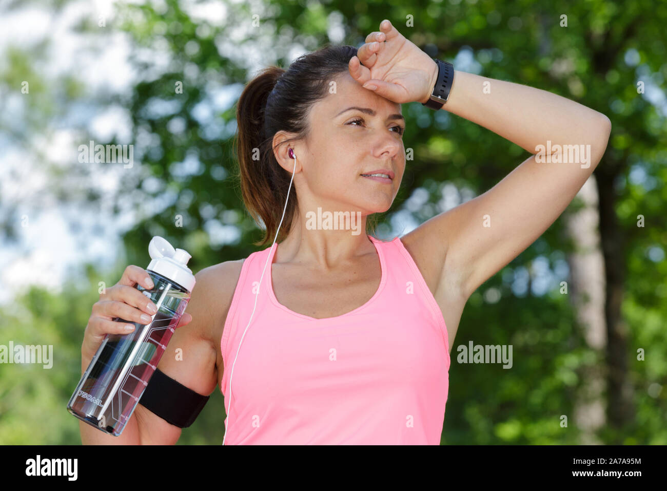 Verschwitzte weibliche Jogger Holding nachfüllbare Flasche Wasser Stockfoto