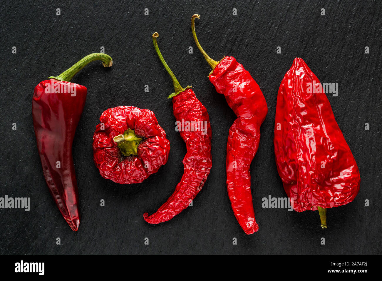Rote getrocknete Banane Pfeffer auf einem dunkelgrauen Schiefer Stockfoto