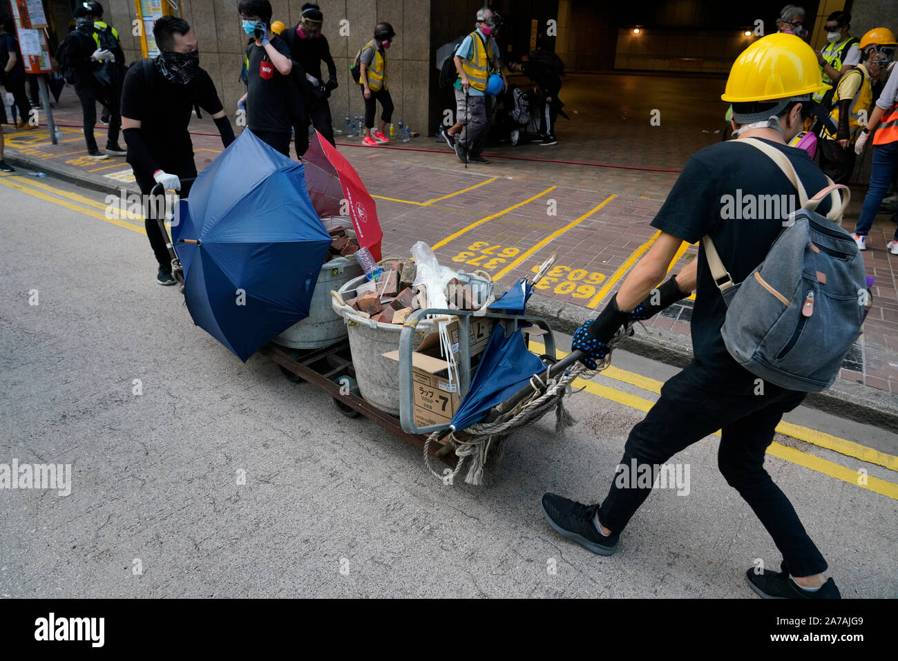Pro-demokratischen Demonstranten bewegen Ziegel auf Wagen in Richtung Polizei Linien in Hongkong Stockfoto