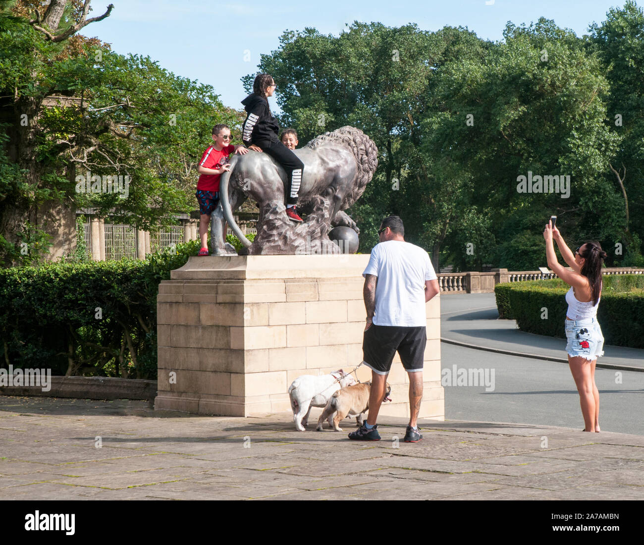 Kinder Foto mit Handy während rittlings lion Statue in italienischen Gärten Stanley Park Blackpool Lancashire England Großbritannien Stockfoto