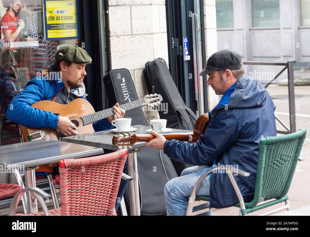 Junge Männer spielen Gitarren im Café draußen, Barthélémy, Rouen, Normandie, Frankreich Stockfoto