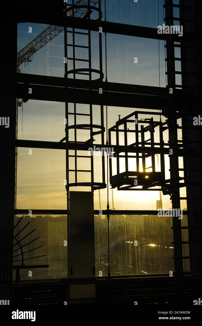 Senkrechte Leiter hinter Sonnenuntergang durch ein Fenster zu sehen Stockfoto