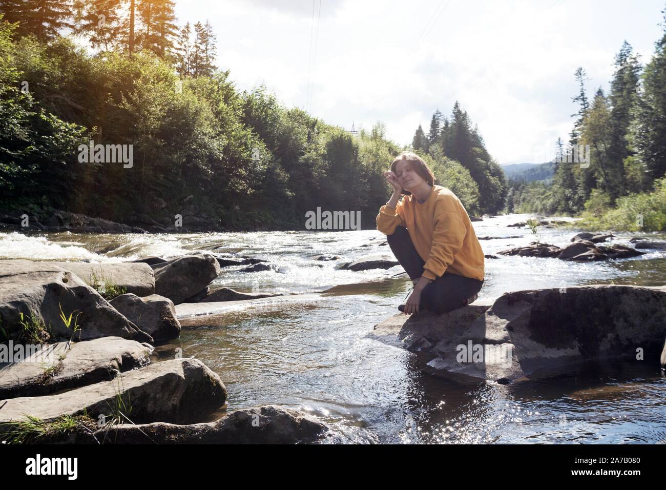 Mädchen Wanderer auf der Bank eines mountain river Stockfoto
