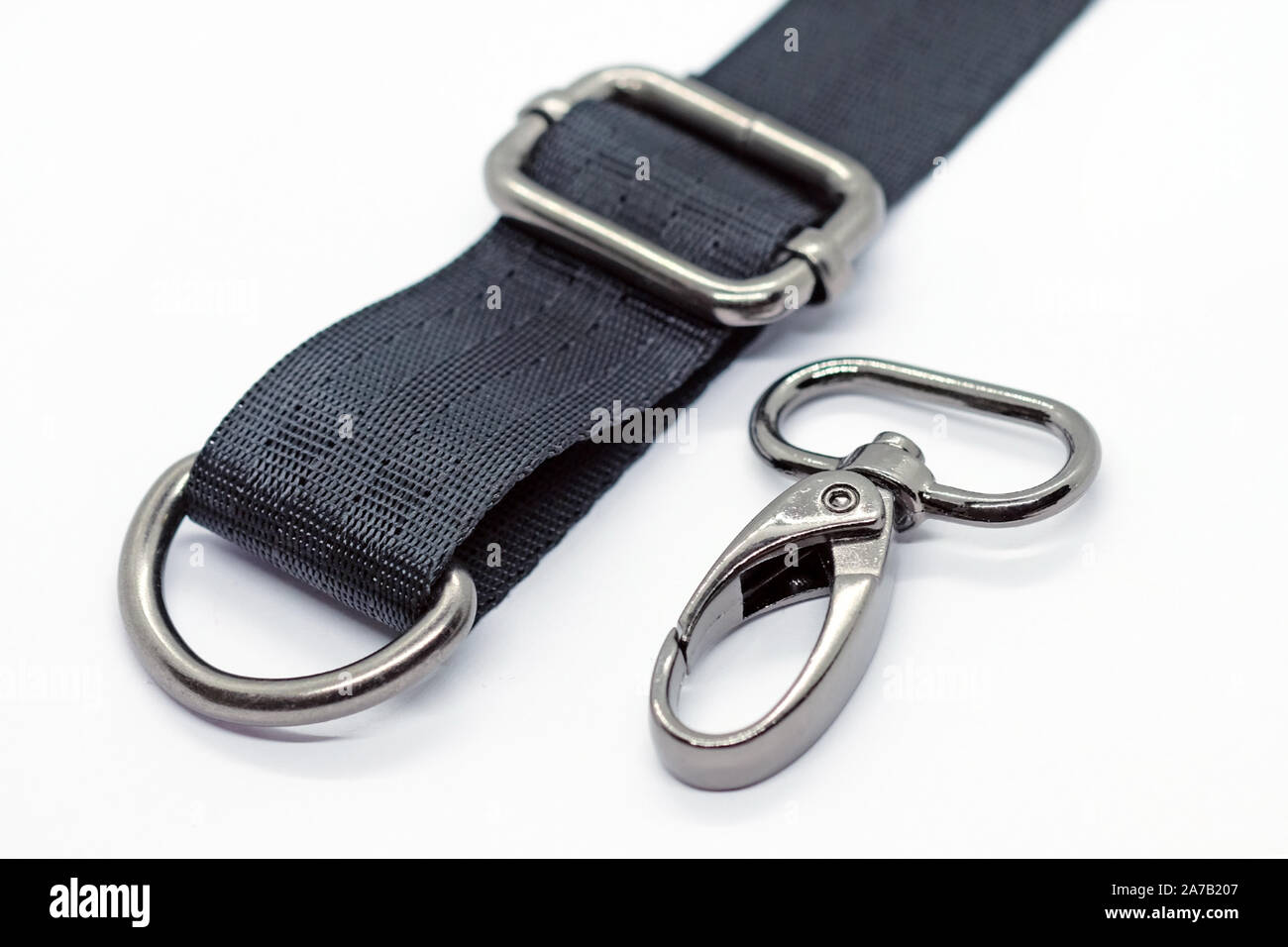 Nähen von Beschlägen für die Herstellung von Taschen und Rucksäcken. Karabiner, halben Ring und Höhenversteller in dunklen Nickel Farbe auf weißem Hintergrund. Schwarzes Band für Stockfoto