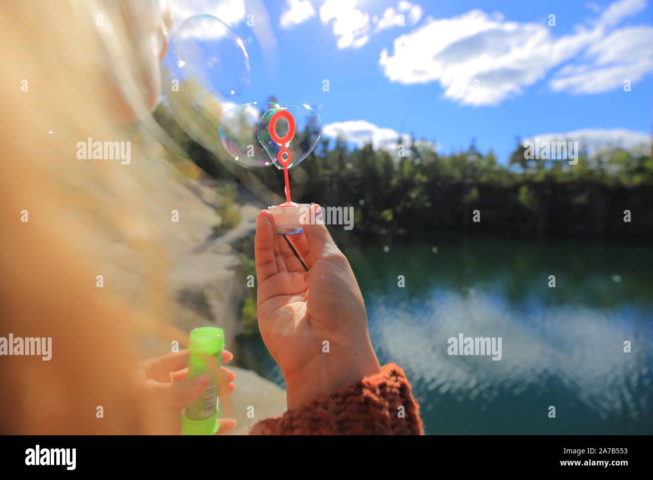 Frau bläst Seifenblasen in der Nähe des Sees Stockfoto