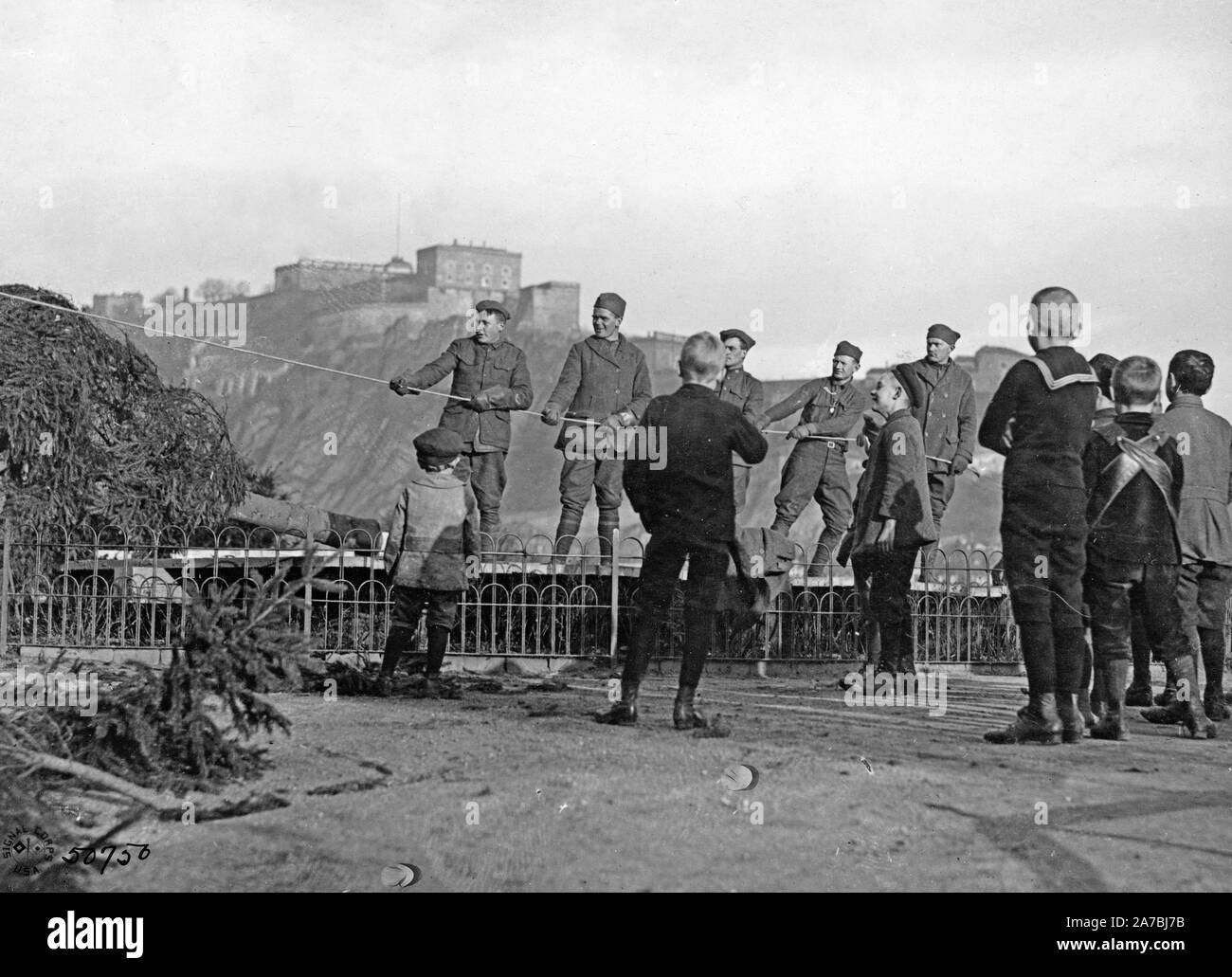 Amerikanische Soldaten auf der Besatzungsarmee, Koblenz, Deutschland, ein Weihnachtsbaum. Deutsche Kinder beobachten das Verfahren. Festung Ehrenbreitstein auf Hügel im Hintergrund. 12/24/1918 Stockfoto
