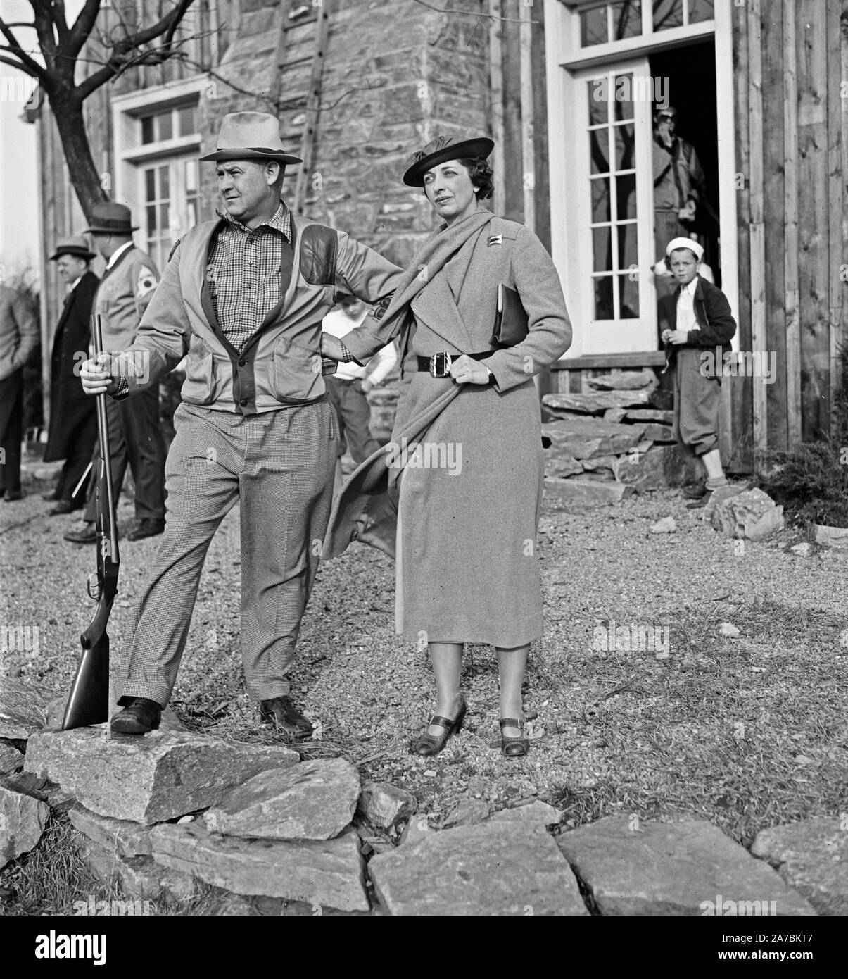 Gut gekleidete Frau mit Mann mit Gewehr, möglicherweise Mitglieder einer Partei schießen kann. 1936 Stockfoto