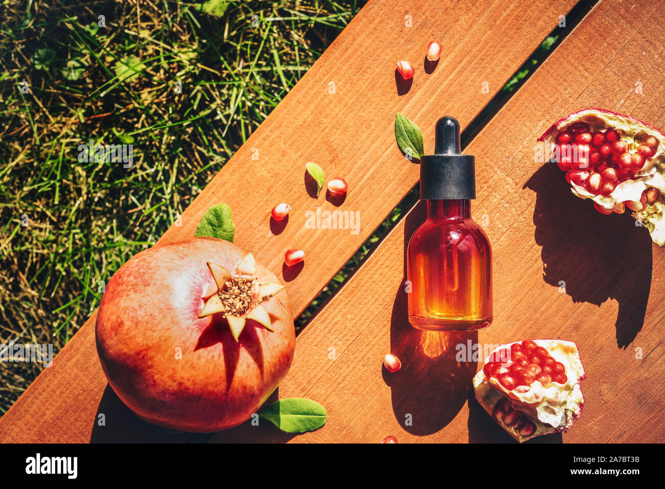 Granatapfel Kernöl in Glas Flasche auf Holz- Hintergrund. Flach, Minimalismus. Konzept der Anti-Aging-Hautpflege Stockfoto