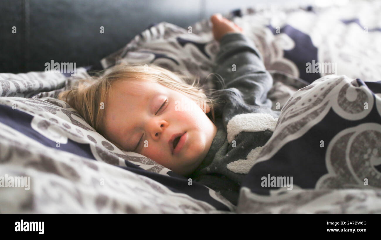 Adorable kleine Kleinkind Mädchen mit blondem Haar Schlupf im großen Bett der Eltern Tag Zeit nap Close-up Stockfoto