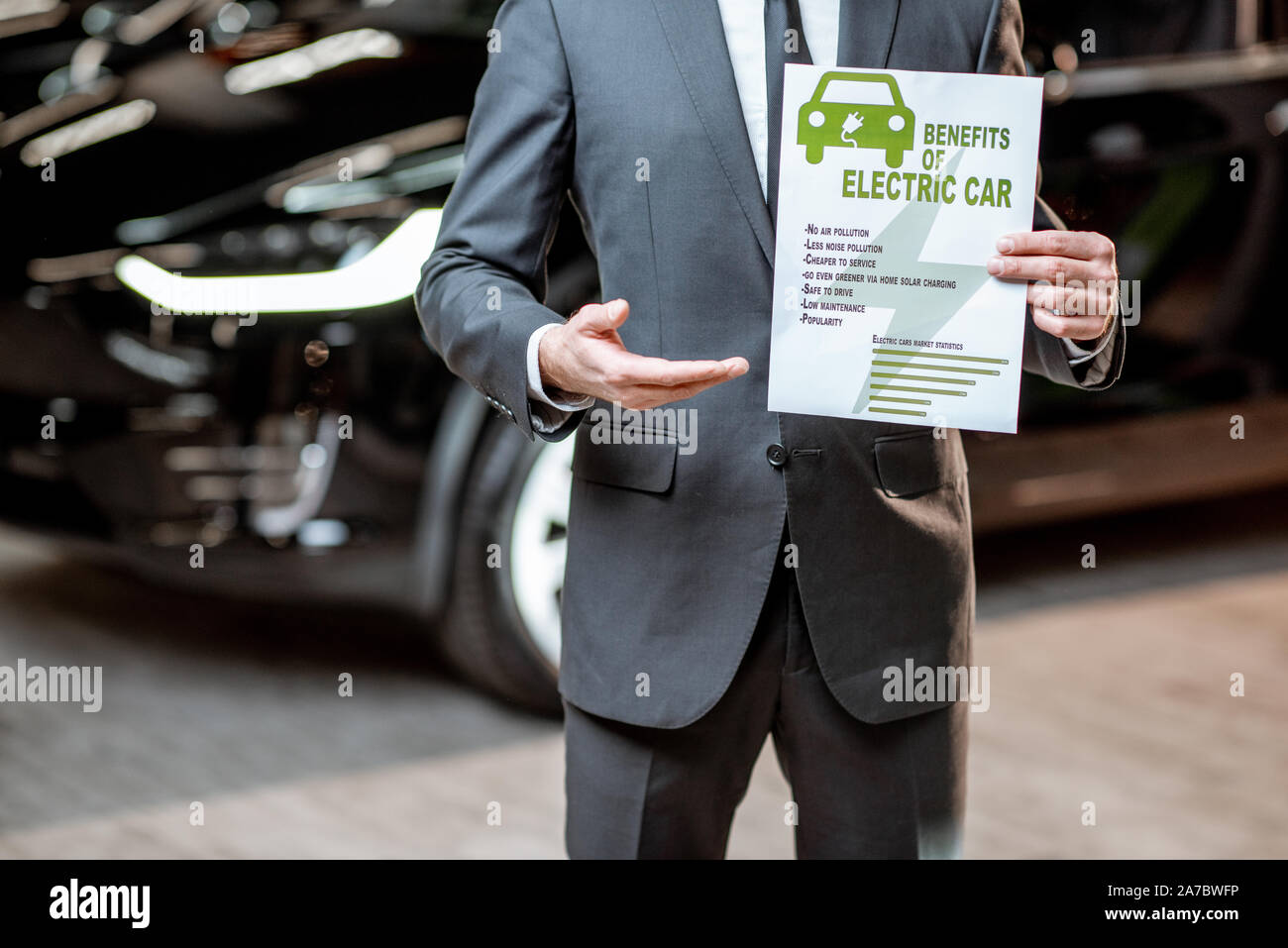 Elegante Sales Consultant zeigt eine Zeichnung zum Thema Umweltfreundliche Elektroautos, Verkauf von Fahrzeugen im Autohaus Stockfoto