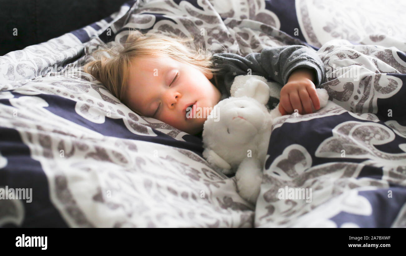 Adorable kleine Kleinkind Mädchen mit blondem Haar Schlupf im großen Bett der Eltern Tag Zeit nap Close-up Stockfoto