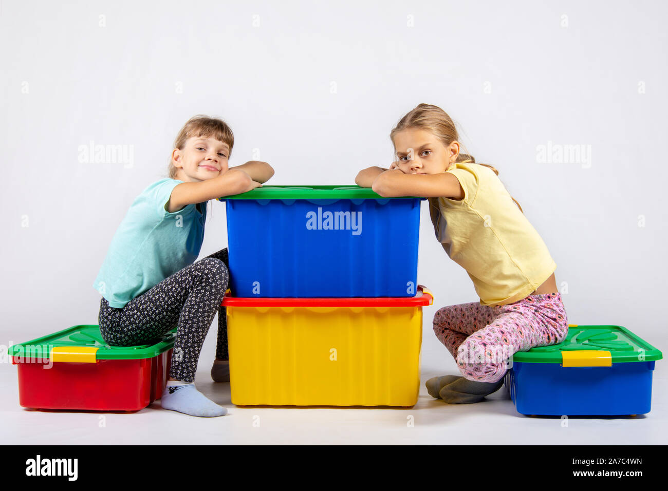 Zwei Mädchen sitzen auf großen Boxen für Spielzeug und sah in dem Rahmen Stockfoto