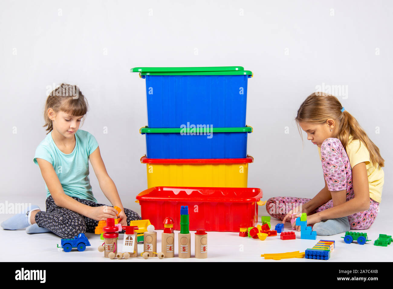 Zwei Mädchen spielen Spielzeug, in der Mitte sind Kisten mit Spielzeug Stockfoto