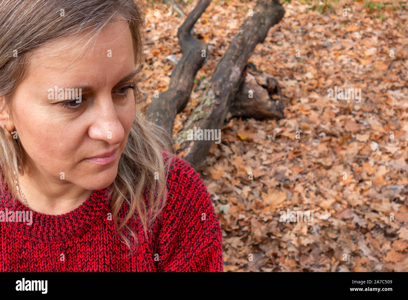 Portrait von reife Frau sitzt auf Baumstamm. Dachte, Meditation oder Zweifel Ausdruck. Mädchen nicht von der Kamera auf die verschwommenen Hintergrund mit Blick kopieren Stockfoto