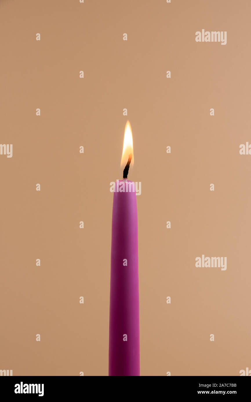 Brennende Kerze, isoliert auf Blass orange Hintergrund Stockfoto