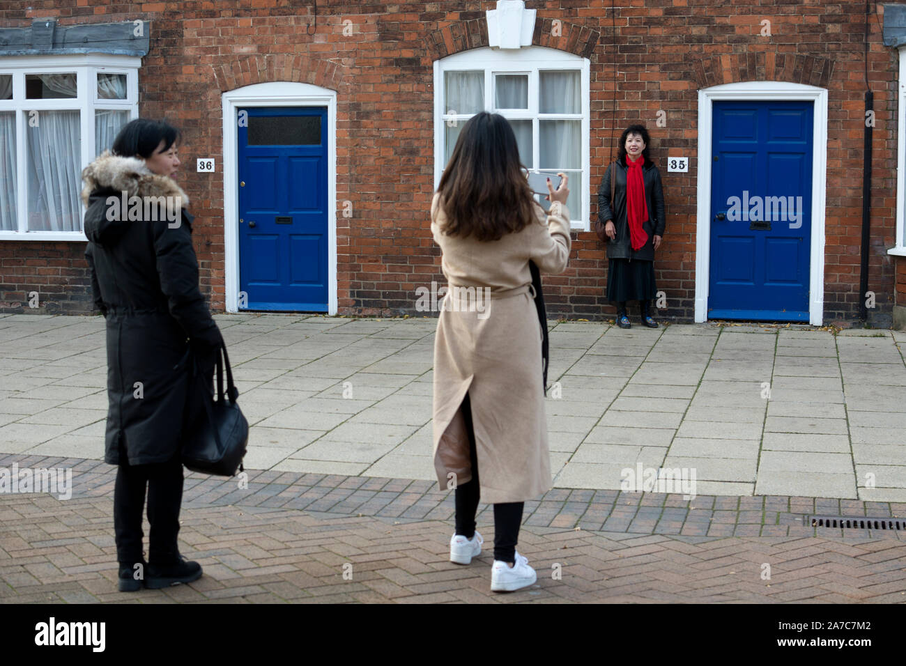 Asiatische Touristen für ein Foto vor einem gewöhnlichen Haus posiert, Stratford-upon-Avon, Warwickshire, Großbritannien Stockfoto