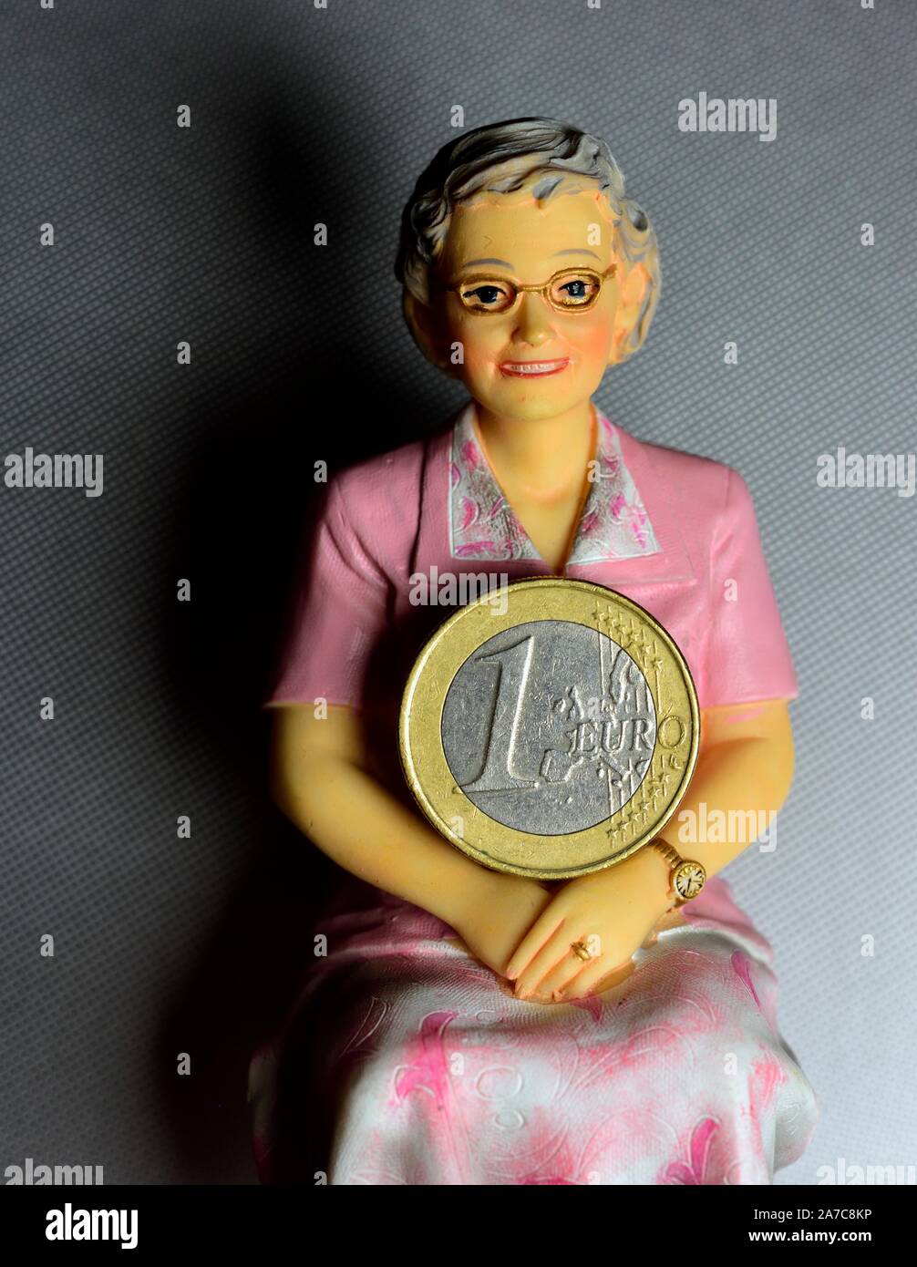 Rentner Figur Holding 1 Euro Münze Stockfoto