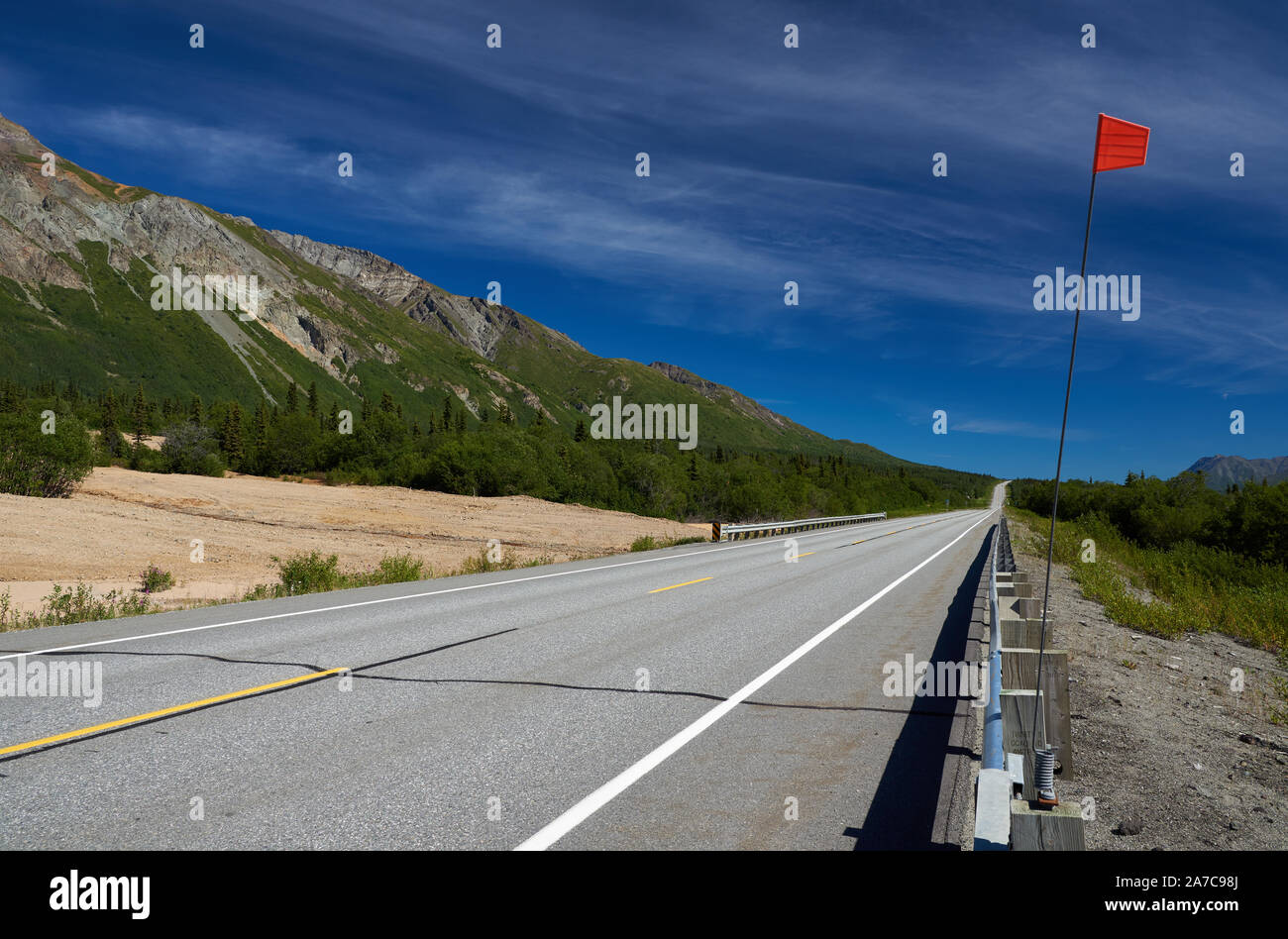 Blick entlang des Glenn Highway am Fuße des Sheep Mountain in Richtung Glennallen, mit einem roten Marker neben der Straße. Stockfoto