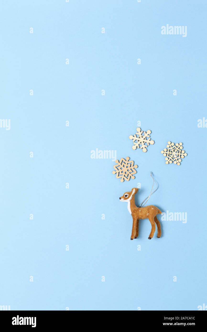 Weihnachtsdekoration, naturalistischen Spielzeug Rehe und drei kleine hölzerne Schneeflocken in Pastell-blaue Hintergrund, kopieren. Festliche, neues Jahr. V Stockfoto