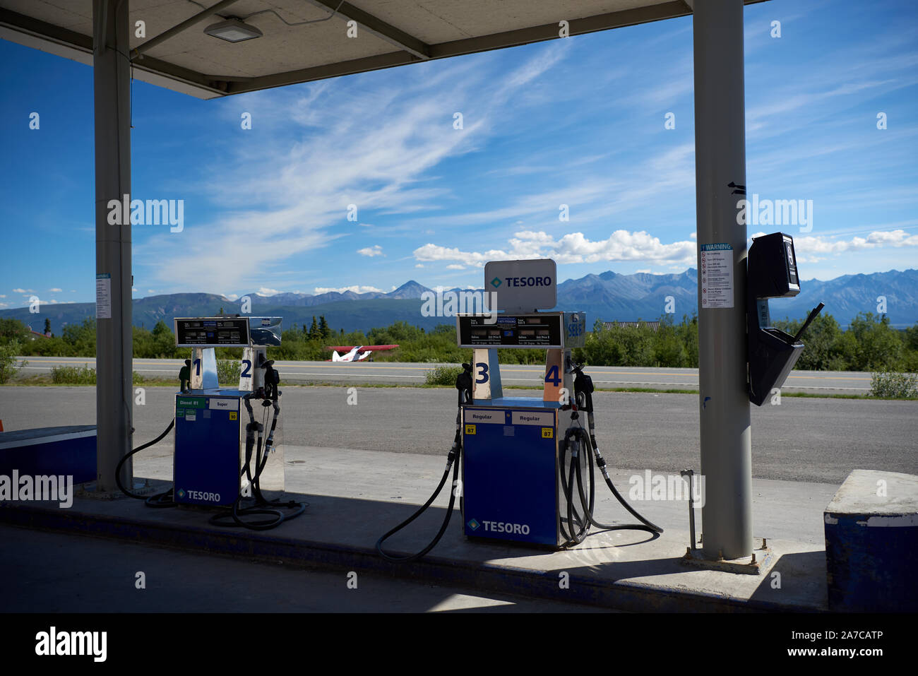 Benzinpumpen an der Tankstelle am Eureka Roadhouse, am Glenn Highway gelegen, mit einem Flugzeug im Hintergrund. Stockfoto
