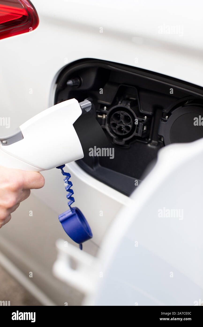 Nahaufnahme von Hand befestigen Sie das Netzkabel auf Umweltfreundliche Emissionsfreie Elektroauto Stockfoto