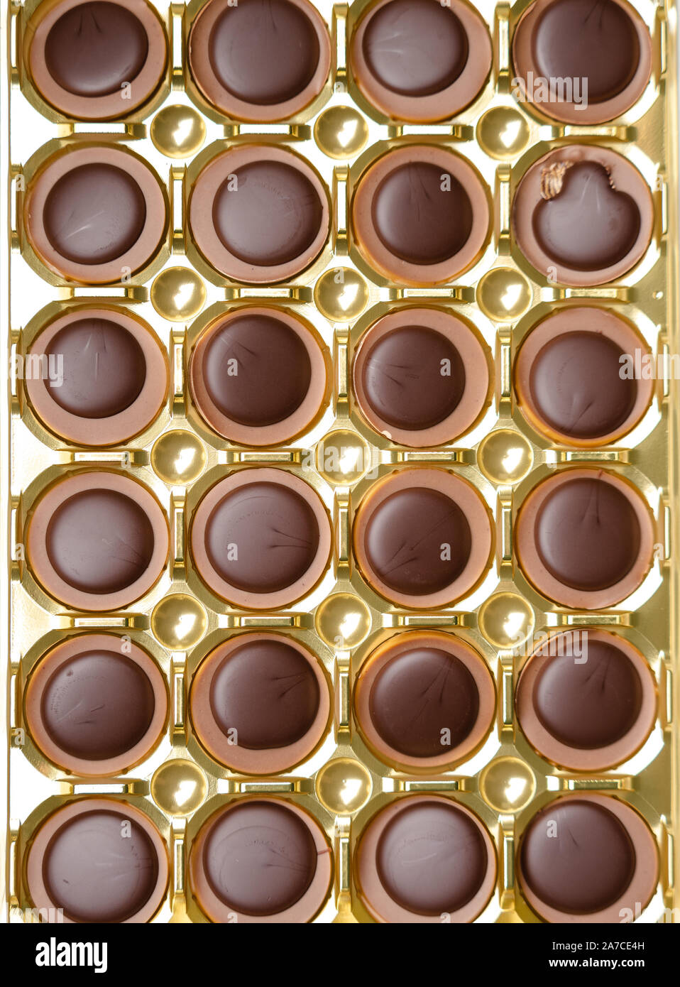 Bonbons Schokolade in einer goldenen Schachtel, Ansicht von oben, glatte symmetrische Reihen für Hintergrund. Muster Schokolade. Stockfoto