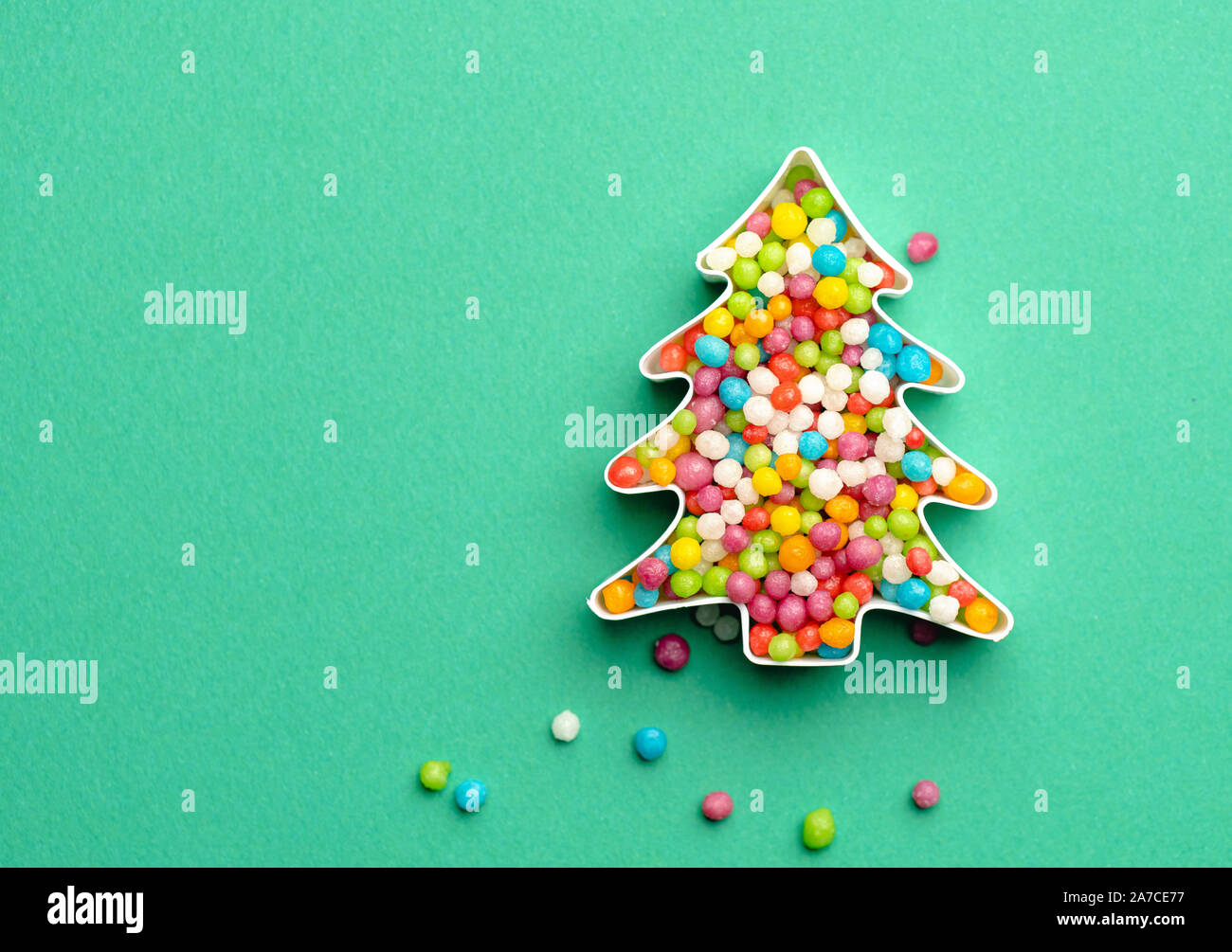 Weihnachtsbaum Form aus vielen farbigen süsse bonbons gemacht. Kreative Gestaltung der Weihnachtsbaum aus bunten Bonbons über grünen Hintergrund. Stockfoto