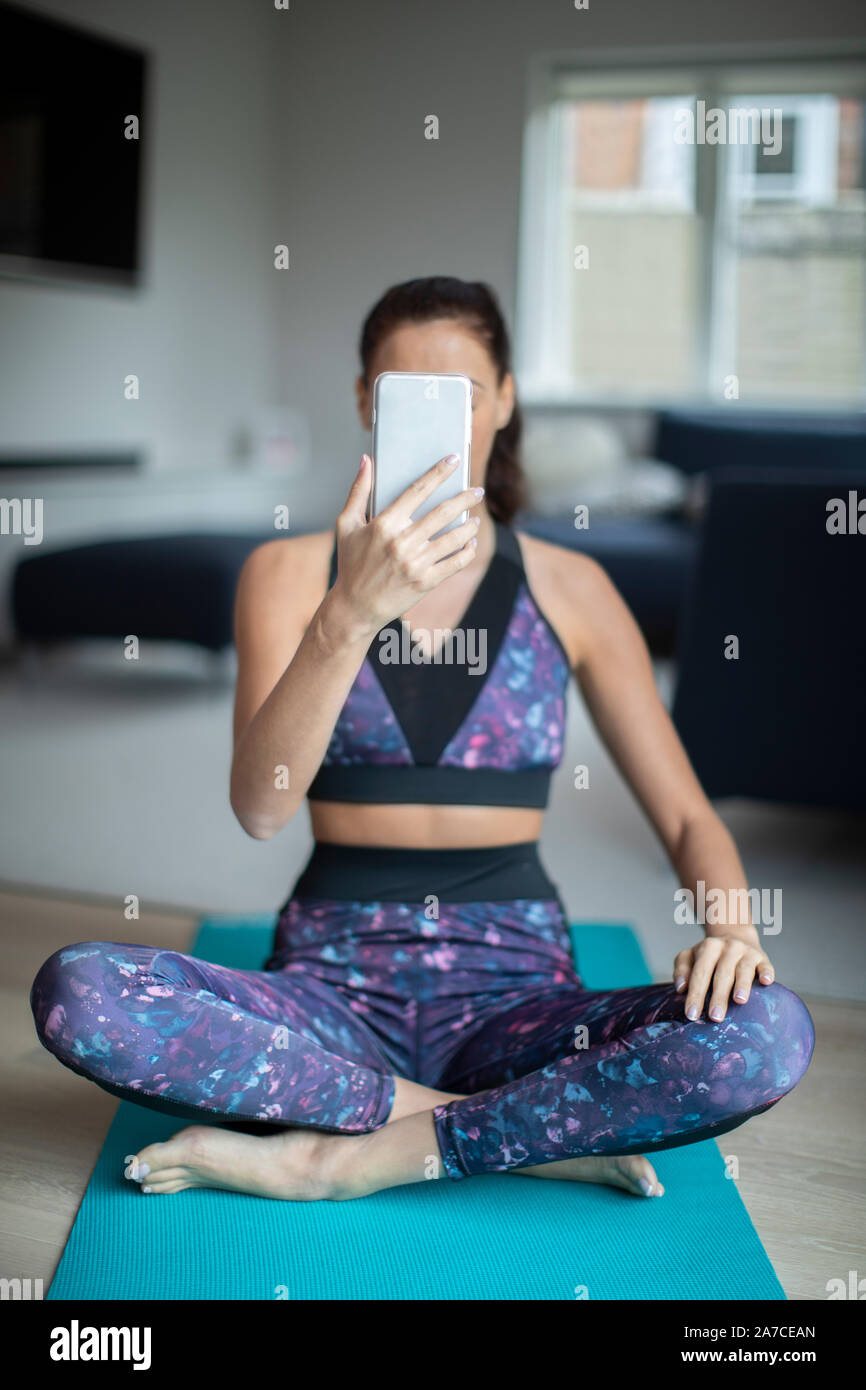Frau Fitness Kleidung Trainieren zu Hause unter Selfie auf Handy Stockfoto