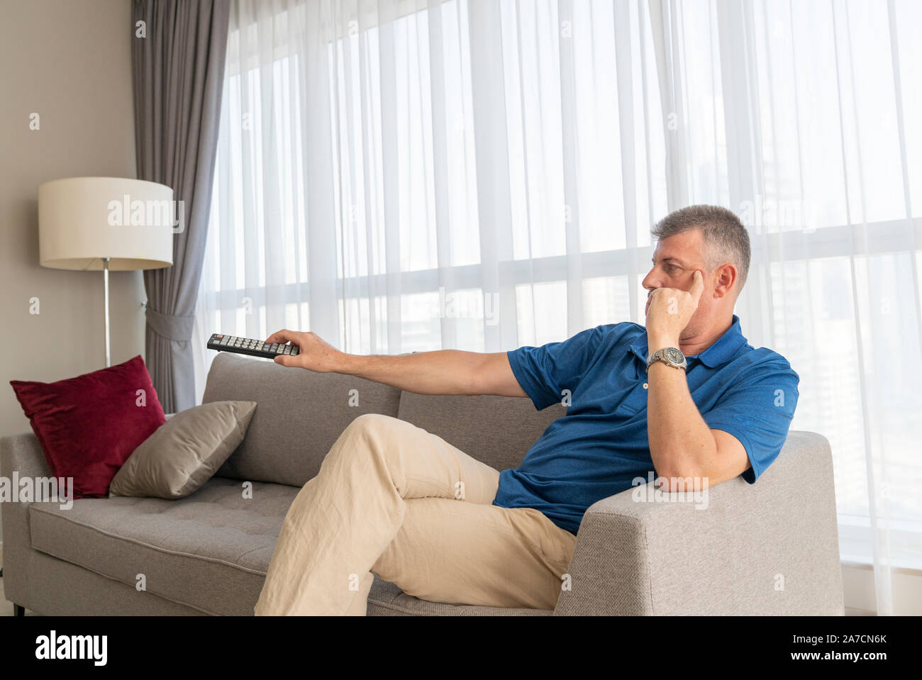 Im mittleren Alter Mann sitzt auf einem Sofa und Fernsehen Stockfoto