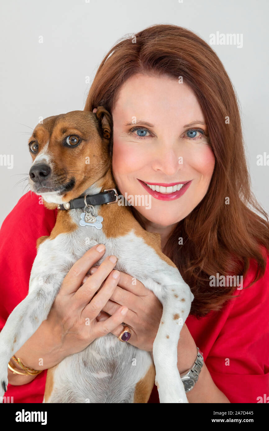 Lächelnde Frau ihr Haustier Hund Holding Stockfoto