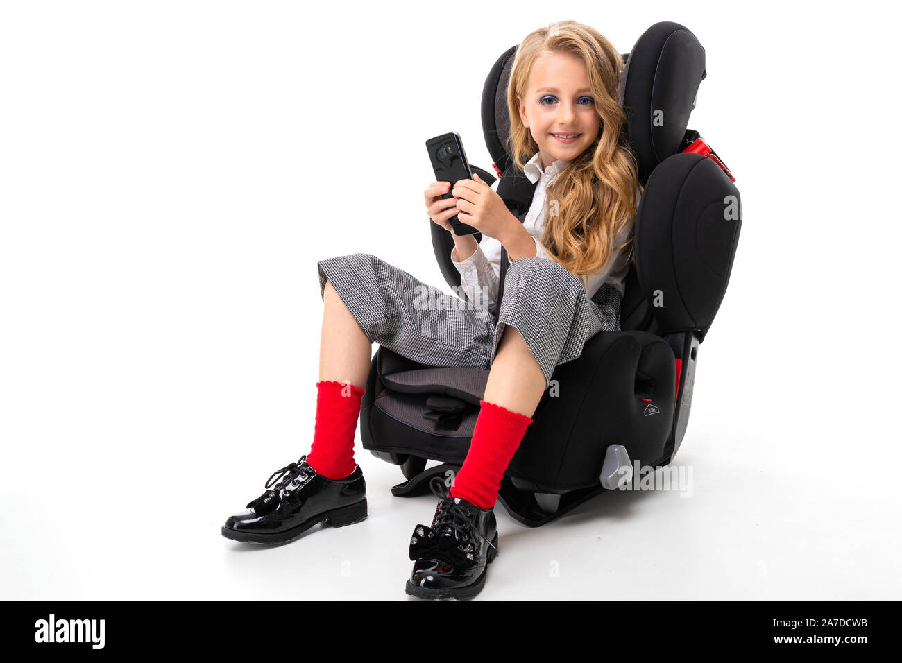 Ein kleines Mädchen mit Make-up und lange blonde Haare in einem Auto baby  Stuhl mit Handy sitzen, mit Freunden chatten und Lächeln Stockfotografie -  Alamy