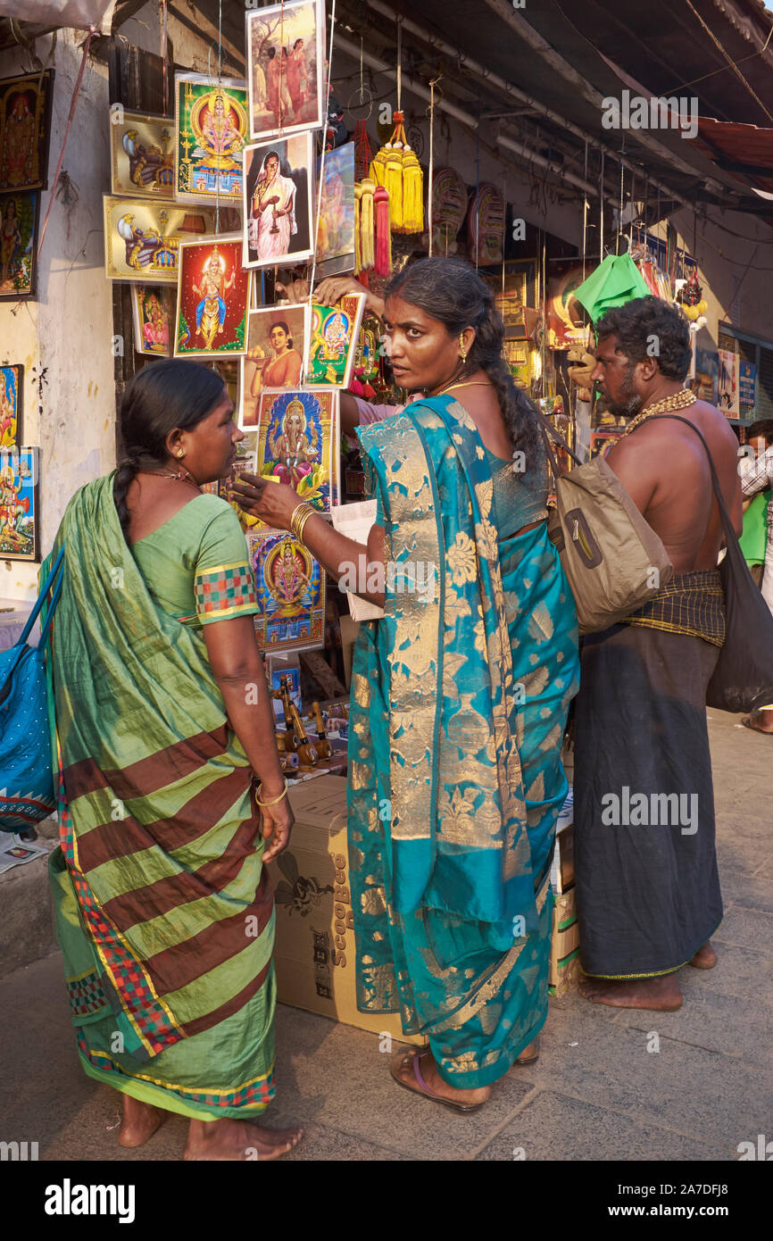 Bei einem Verkauf Abschaltdruck außerhalb Padmanabhaswamy Temple in Trivandrum, Kerala, Indien, eine Besucherin unter einer Anzahl von Bildern mit hinduistischen Gottheiten wählt Stockfoto