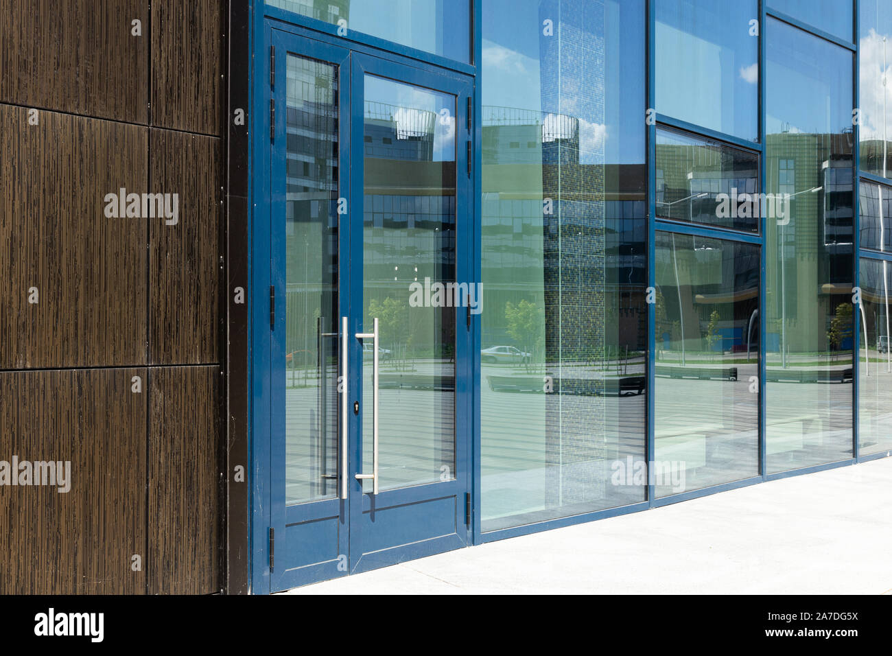 Diagonaler Sicht der modernen Gebäude mit bif Glas, Fenster und Tür mit blauen Rahmen. Straße Reflexion. Stockfoto