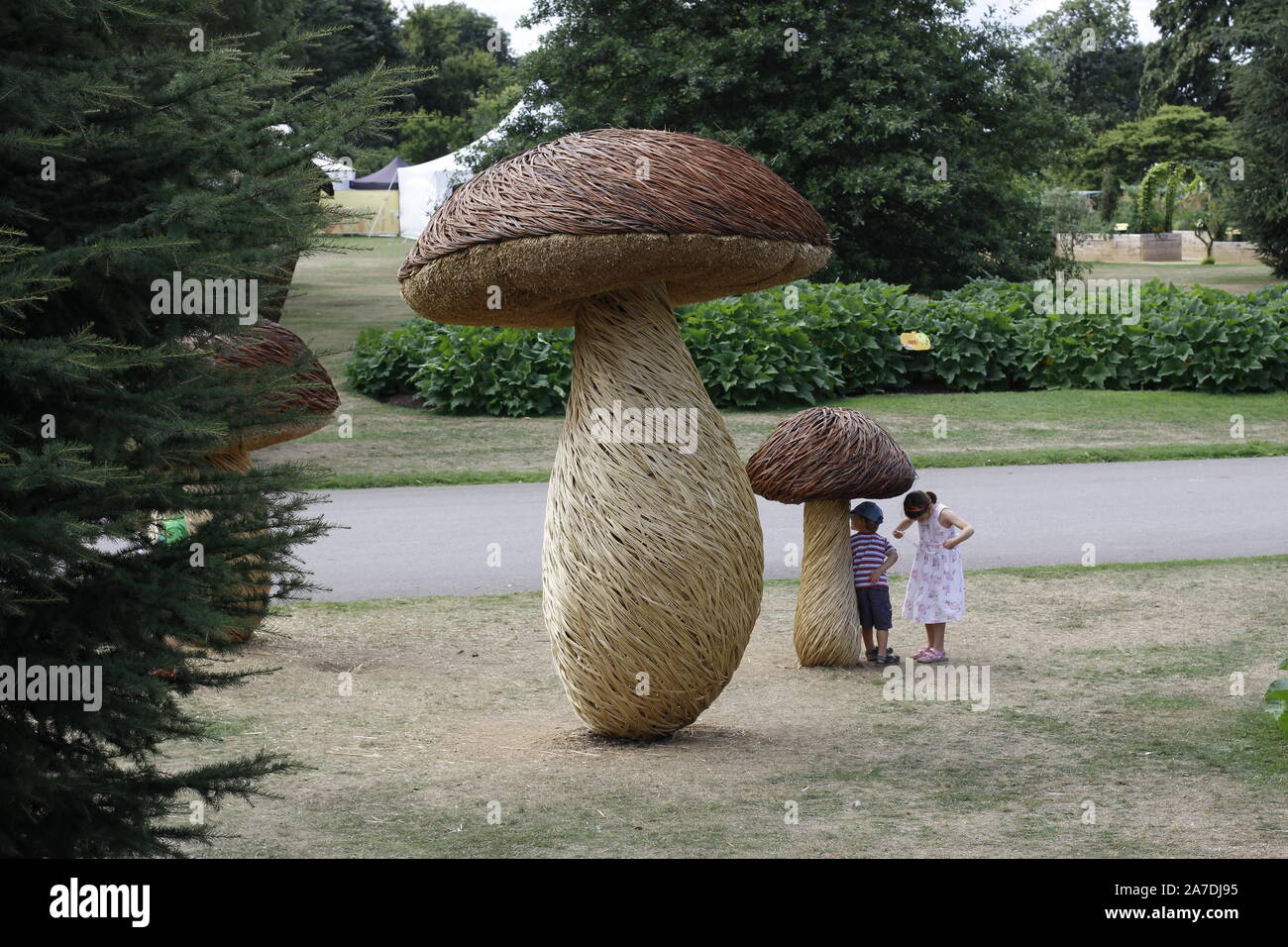 Kinder spielen unter einem riesigen Mann, Pilz oder Fliegenpilz in einem Garten Stockfoto