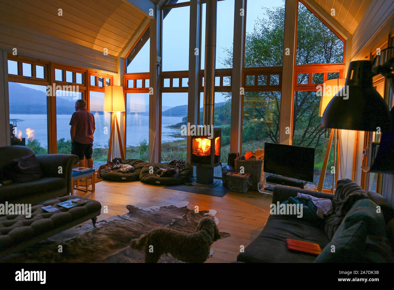 Ein Mann in einem Luxus Chalet auf der Rahoy Immobilien Blick aus dem Fenster in Richtung die Ufer des Loch Teacuis, Morvern, Scottish Highlands, Schottland Stockfoto