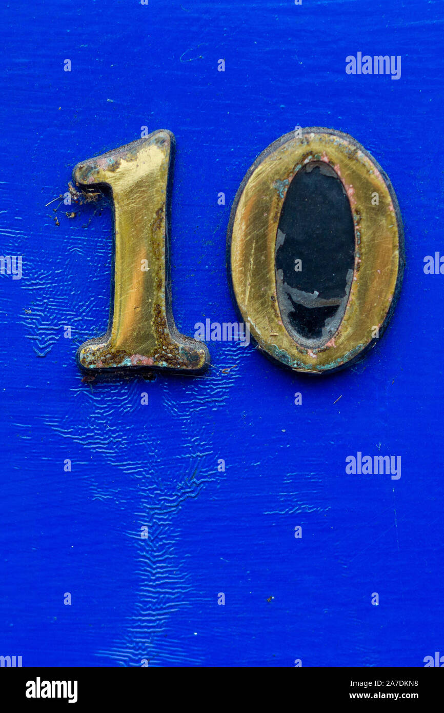 Bronze Hausnummer 10 auf einem hellen Blau Holz- Vordertür Stockfoto