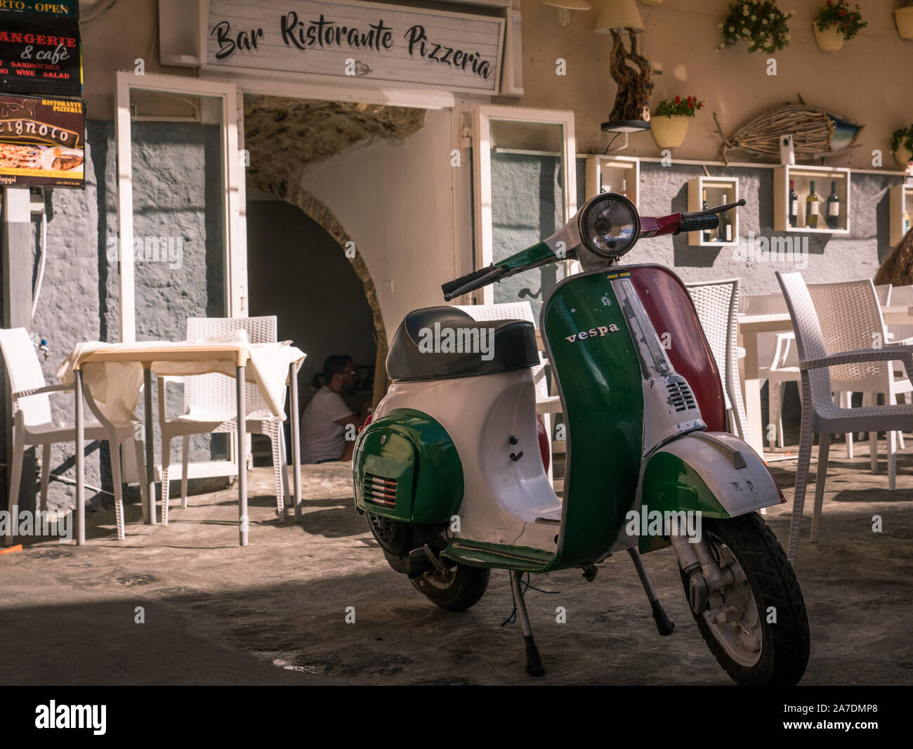 Vespa Motorrad in den Farben der italienischen Flagge vor der traditionellen Restaurant und Pizzeria mit Schriftzug in Tropea, Kalabrien, Italien Stockfoto