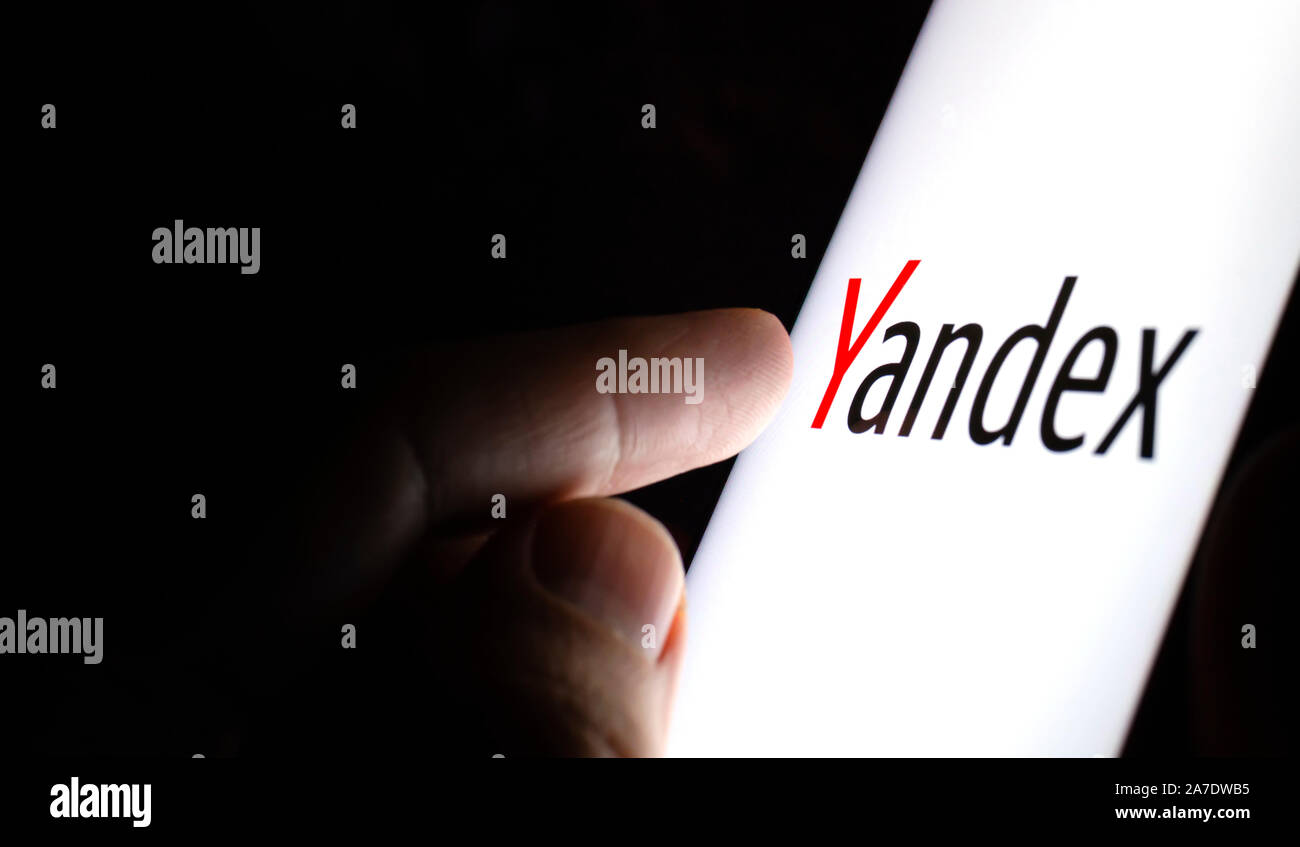 Yandex Logo auf einem Bildschirm des Smartphones in einem dunklen Raum und einen Finger zu berühren. Stockfoto