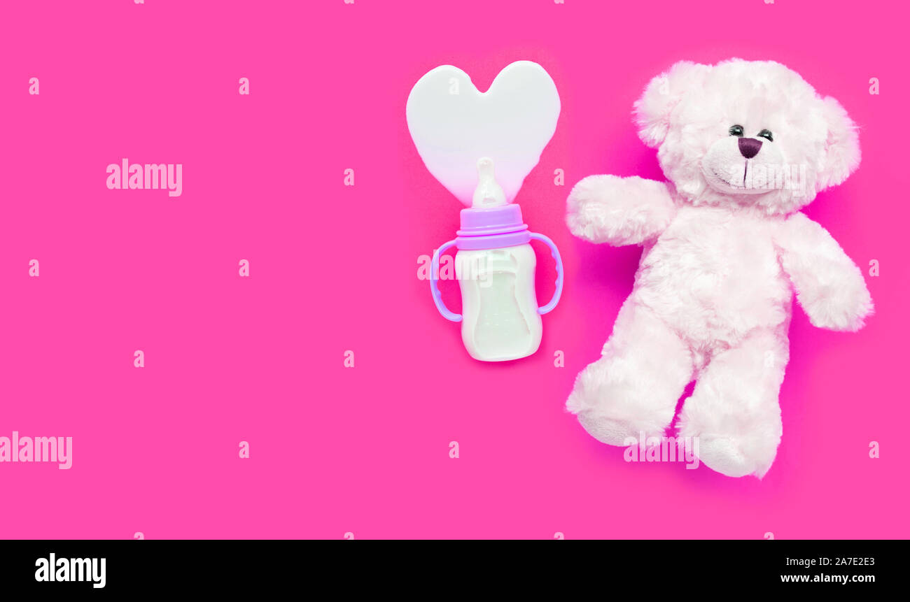 Flasche Milch für das Baby mit Spielzeug weiß auf rosa Hintergrund. Platz kopieren Stockfoto