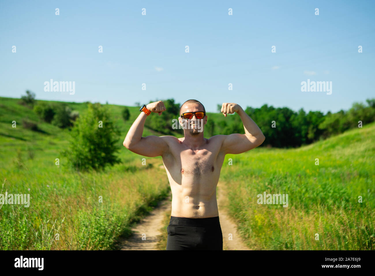 Athletischer Mann in Sonnenbrille ohne t-shirt zeigen Bizeps Stockfoto
