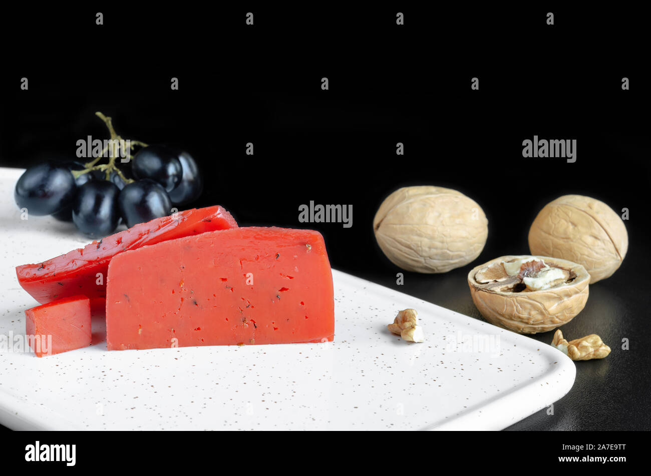 Roter Käse, Nüsse und Trauben auf dem Brett Stockfoto