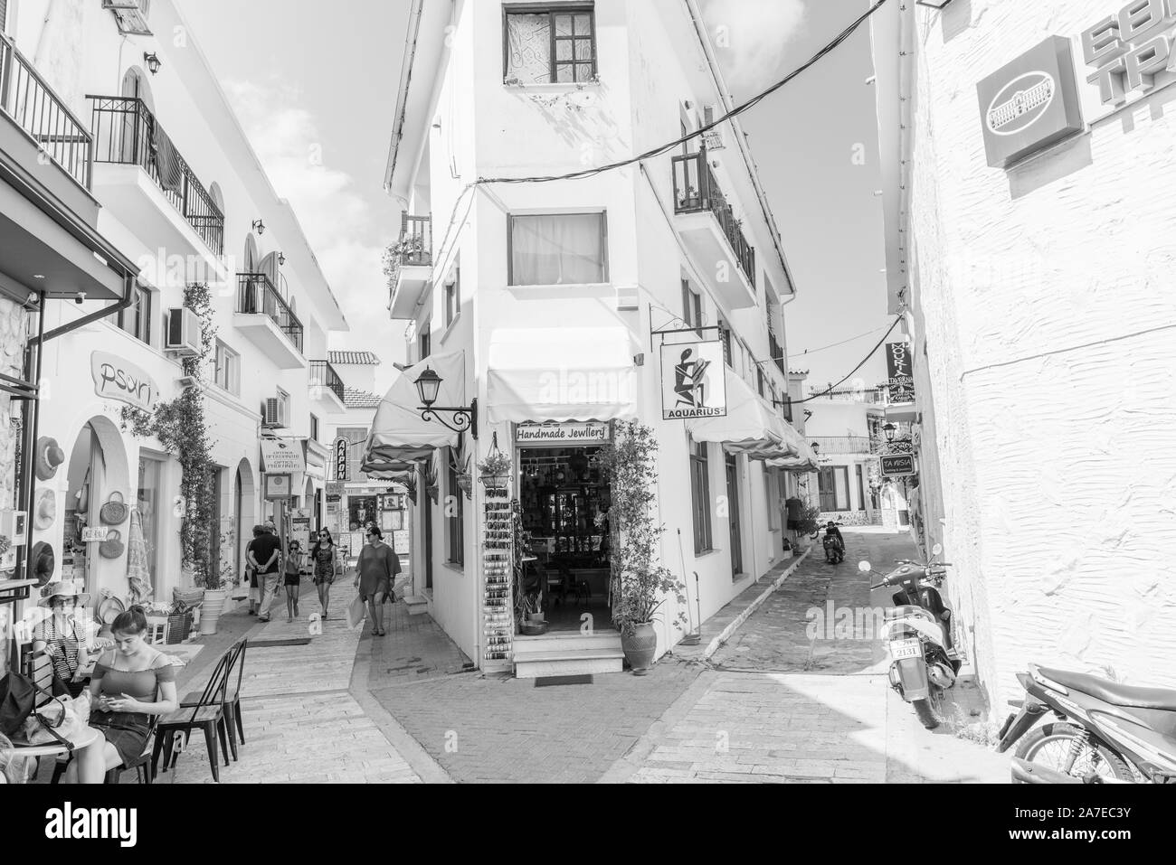 Skiatthos Griechenland - 31. Juli 2019; Skiathos street scene in Schwarzweiß. mit Menschen frühstücken und zu Fuß entlang der engen Gassen. Stockfoto