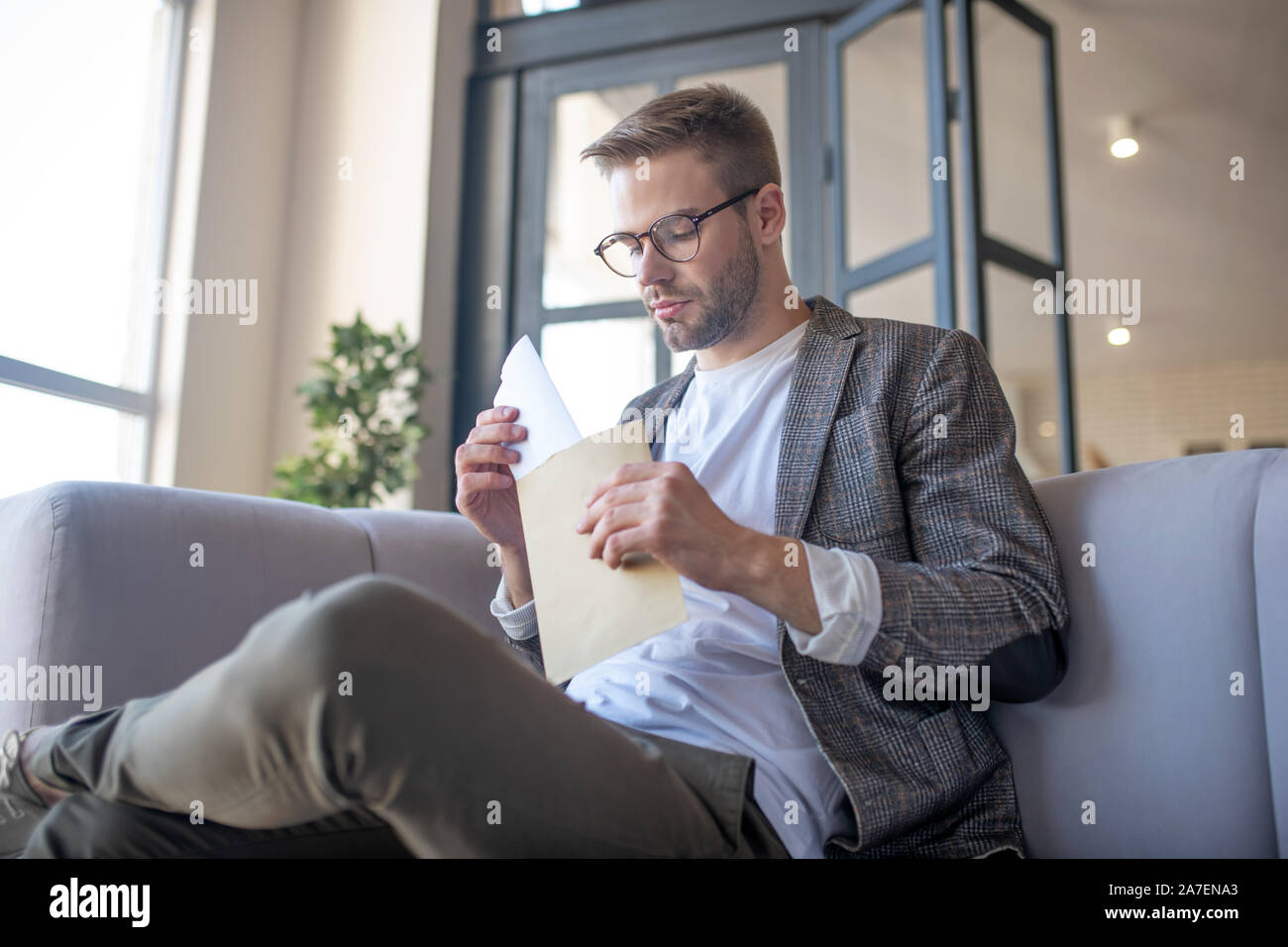 Bärtiger Mann in Gläsern mit Umschlag mit Schreiben Stockfoto